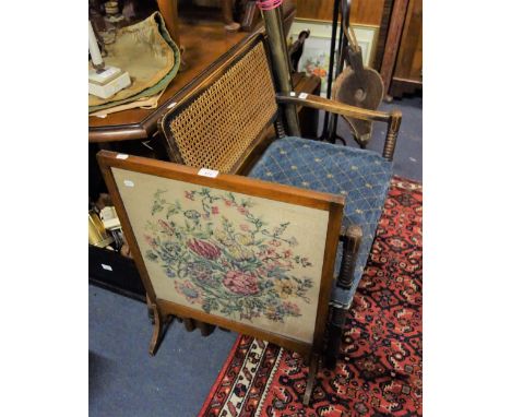 A BEECH FRAMED ARMCHAIR with upholstered seat and caned back with bobbin turned legs and stretchers and a needlework firescre