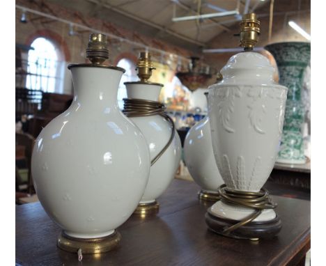 A SET OF THREE WHITE CERAMIC TABLE LAMPS with gilt metal fittings and a similar white moulded ceramic lamp on a wooden base