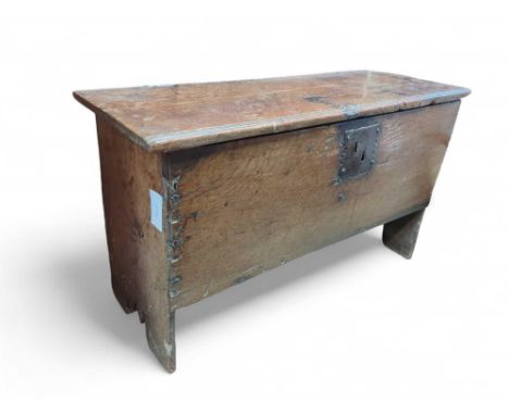 A small oak coffer upon straight legs that also constitute the sides of the body. The hinges being links pinned into the wood