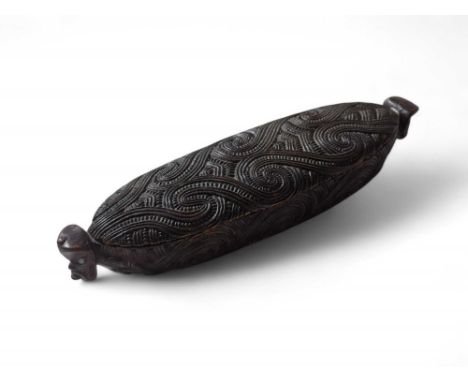 A Maori Wakahuia or feather box from New Zealand, of canoe shape carved all over with haehae and notching, Tiki mask terminal