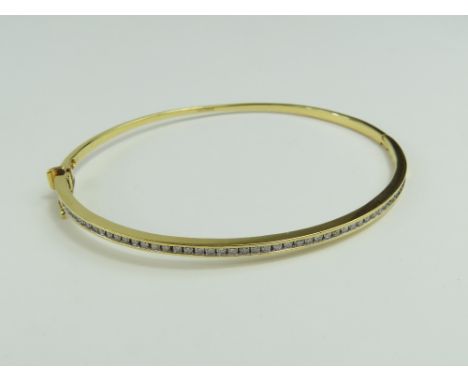 A slim gold bangle set with round brilliant cut diamonds, the channel set stones with a total weight of approximately 0.50ct,
