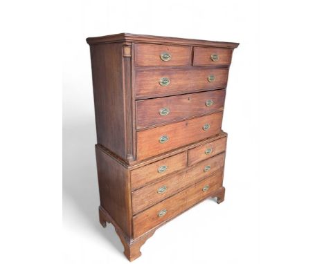 A Regency era stained oak chest on- chest, with brass swing handles off oval discs, corner column features and overall upon d