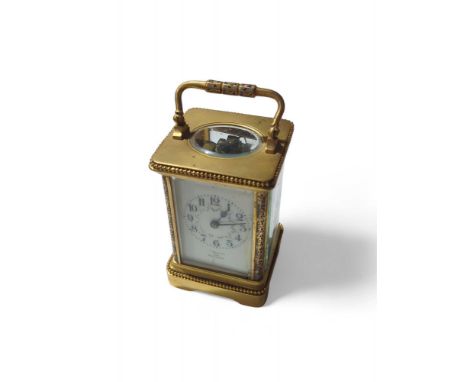 A late 19th Century brass cased carriage clock with champleve decoration and having cream enamel dial inscribed “Woodward Der