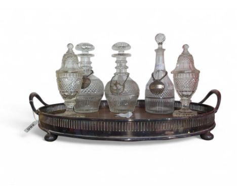 A silver-plated tray with wooden body, alongside five cut-glass decanters, three with silver labels. The tray with a gallery-