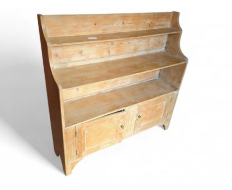 A 20th-century pine sideboard of unique form, with two cupboard doors under three fixed shelves that grow narrow with height.