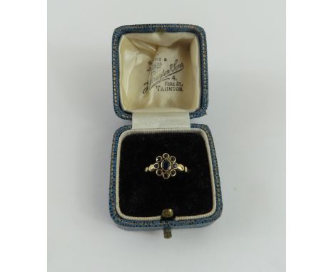 An unusual 9ct gold sapphire cluster ring, the oval cut stone rub over set with a row of round cut stones around it, finger s
