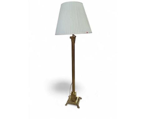 A brass lamp with white shade. The lamp in the form of a column, with square base supported by four claw feet at each corner.