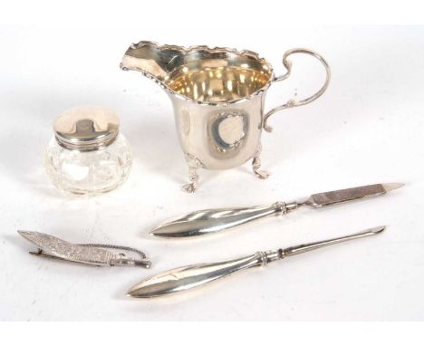 Mixed Lot: A small George V silver cream jug having a castellated rim, scroll handle and supported on three cast trefoil feet