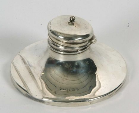 An Edwardian silver capstan ink well with integral pen rest to be base, having hinged finial lid, glass lined reservoir (load