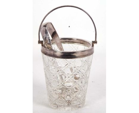 A vintage cut glass ice bucket with silver plated rim and swing handle drainer together with a pair of ice tongs