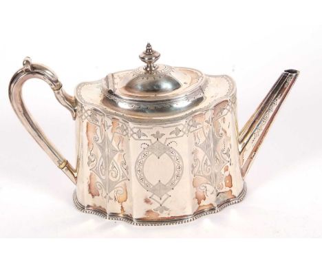 A Victorian silver teapot of shaped oval form, the panelled sides chased and engraved with a geometric design with opposite v