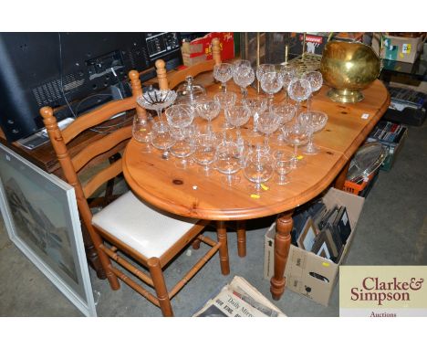 A pine extending dining table with a set of three ladder back chairs