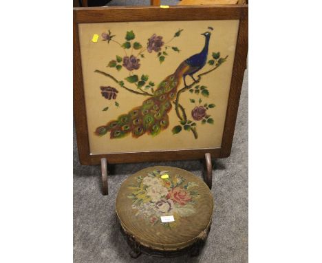 A VINTAGE OAK FIRESCREEN WITH PEACOCK DESIGN TOGETHER WITH A CARVED TAPESTRY TOP MAHOGANY FOOT STOOL