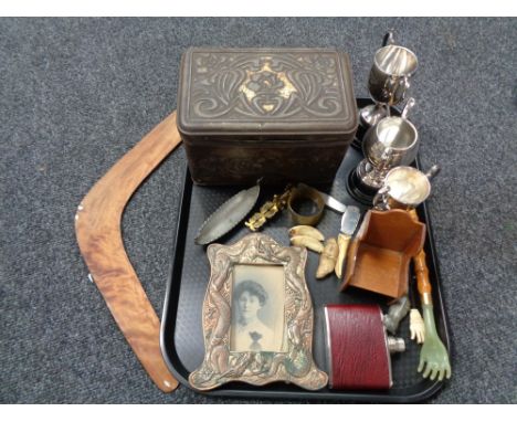 A tray of miscellany to include plated trophies, antique embossed tin, boomerang, hip flask, sovereign scales, oriental coppe