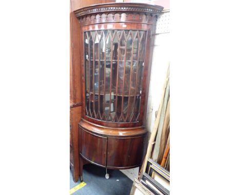 A GEORGE III STYLE BOW-FRONT GLAZED CORNER CABINET WITH DENTIL CORNICE