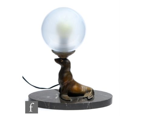 Unknown - An Art Deco bronzed spelter table lamp modelled as a seal with painted eye decoration, below a spherical frosted gl