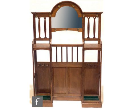 In the manner of Liberty &amp; Co - An oak hallstand, the central arched mirror flanked by pierced laths and brass hat and co