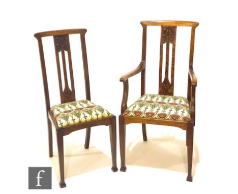 In the manner of Liberty &amp; Co - A set of six oak dining chairs, the pierced backs with carved stylised seed pod detail to