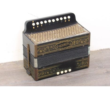 A Hohner button melodeon, gilded design on a black body 