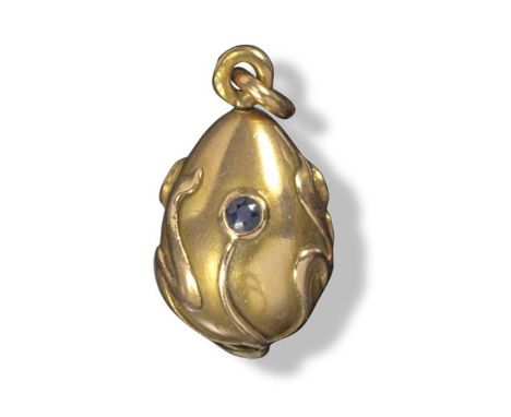 An Art Nouveau gold miniature egg pendant by Fabergé, applied with scrolling foliate decoration and three small sapphire styl
