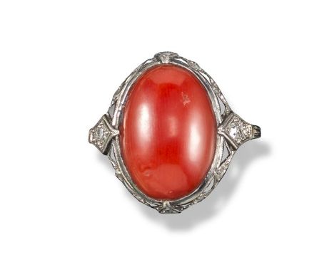 An Art Deco coral ring, c.1925, mounted with an oval-shaped coral cabochon in platinum with a border of triangular black onyx