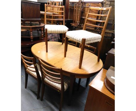 A mid century dining table and six chairs, hardwood finished chairs in a ladder back style, with fabric padded coverings to t