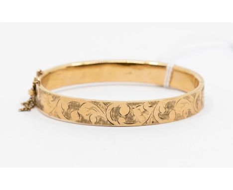 A 9ct gold hinged bangle, hollow form with machine engraved foliate decoration to top, width approx 9mm, internal diameter ap