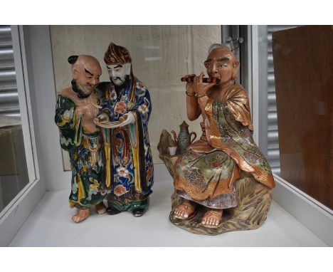 A Chinese figural group of two men reading a scroll and a God playing flute beside teapot and tea bowl (2)