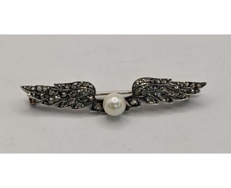 A 19th century white metal brooch in the form of wings, inset with old cut diamonds and a pearl to the centre, tested as 9ct,