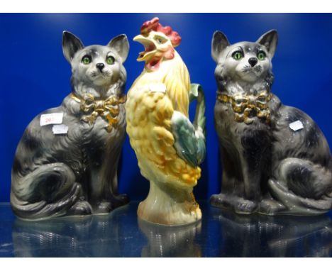 A PAIR OF EDWARDIAN GLAZED POTTERY CATS, with green glass eyes circa 1908 and a glazed ceramic cockerel jug 