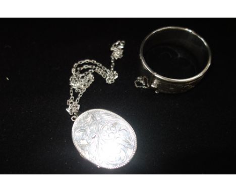 A SILVER BANGLE and a locket attached to a silver chain