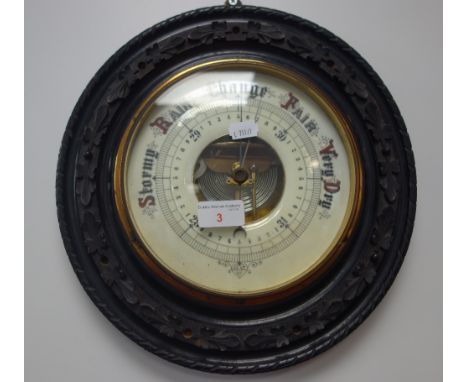 A 19TH CENTURY ANEROID BAROMETER in carved and ebonised circular frame