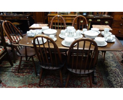 ERCOL; A STAINED ELM DINING TABLE with five stick back chairs