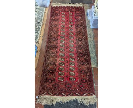 A Bokhara runner, on a red ground, 103cm x 203cm