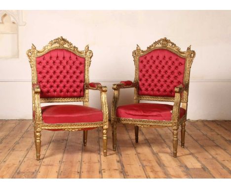 A pair of Louis XVI style carved giltwood armchairs, each having a red button upholstered back, h.109cm