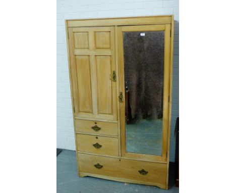 An early 20th century ash wardrobe, the flat top over a panelled and mirrored doors and an arrangement of three drawers,  184