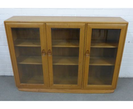 An Ercol light elm bookcase with three glazed doors, 136 x 98 x 31cm