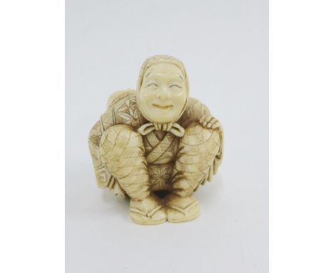 An early 20th century Japanese carved ivory Netsuke of Yakuharai the Oni hunter, modelled seated with a large sack on his bac