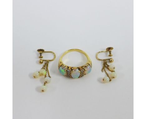 An opal and diamond ring with three opals and two rows of three diamonds, set in an unmarked gold band with pierced shoulders