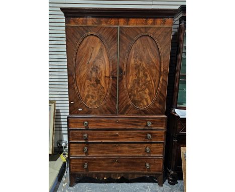 Sheraton period mahogany linenpress with fitted sliding trays and enclosed by a pair of oval panel doors and four long gradua