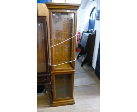 A contemporary oak freestanding display cabinet, having a single door over a second glazed door, raised on a plinth base