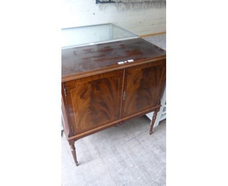 A reproduction flame mahogany twin door cocktail cabinet of small proportions, the twin panelled doors enclosing fitted inter
