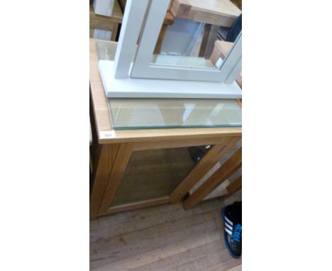 A modern light oak glazed music cabinet, with three enclosed glass shelves.