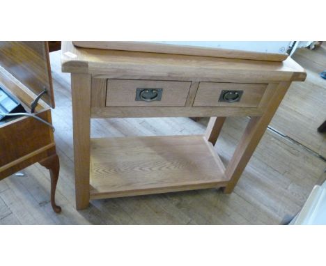 A contemporary light oak  side table with a slab top above two frieze drawers each with metal drop handles and a pot board.