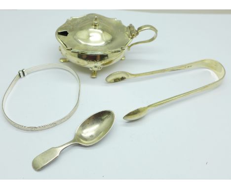 A silver mustard with liner, a pair of Victorian silver sugar bows, a small silver caddy spoon and a bangle, 83.6g 