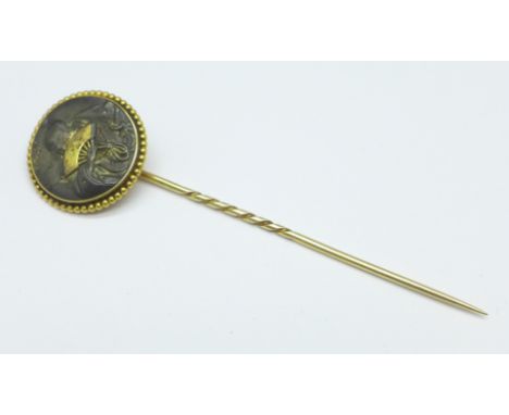 A yellow metal set stick pin decorated with an image of a Japanese gentleman with fan and sword, diameter 2cm 