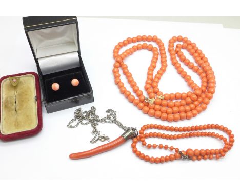 A twig coral pendant on a silver chain, a coral necklace, a large coral coloured bead necklace, a pair of earrings and a stic