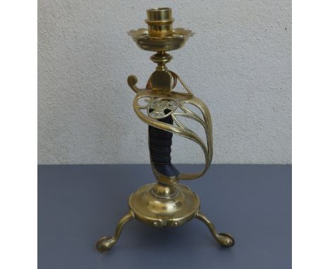 A  Victorian sword hilt candlestick on tripod brass cavalry spur feet,  12" high.
