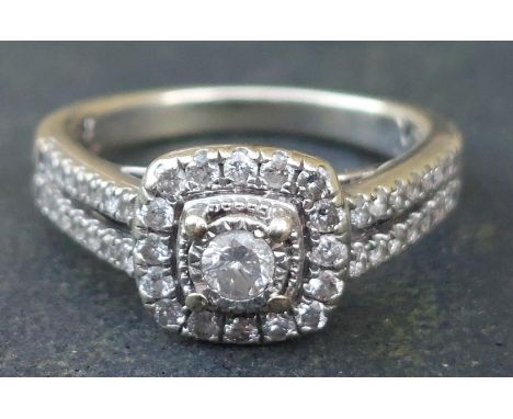A modern diamond cluster ring with twin rows of diamonds to shoulders, in 9ct white gold.  Finger size K.