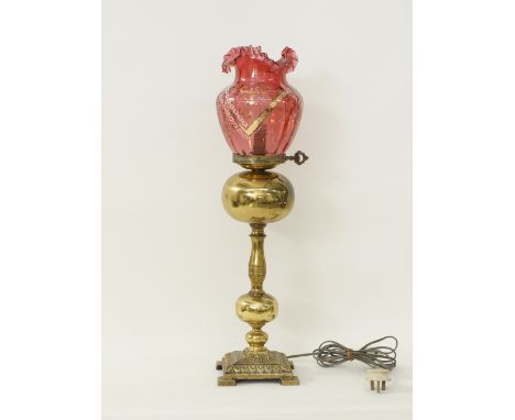 A gilt metal table lamp with a Bohemian red glass shade with enamelled decoration, H63cm, early to mid 20th century.